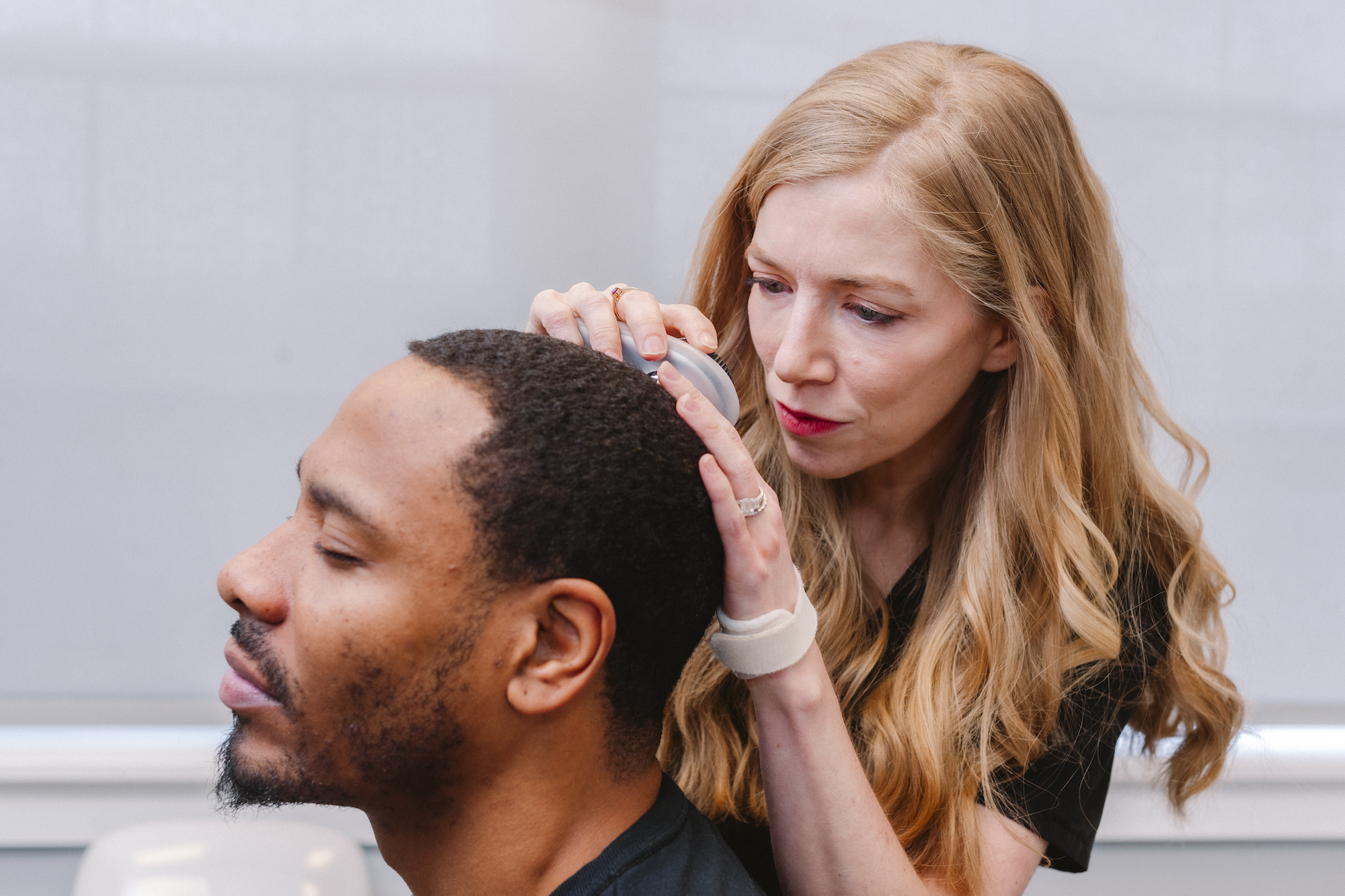 Female dermatologist examining Black patient's scalp